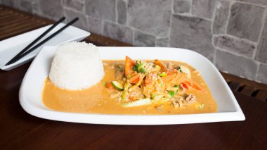 Köri soslu sığır eti ve pirinç ile servis edilen sebzeli Asya tabağı..