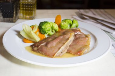 Domuz filetosu domuz pastırması ve sebzeyle sarılmış..