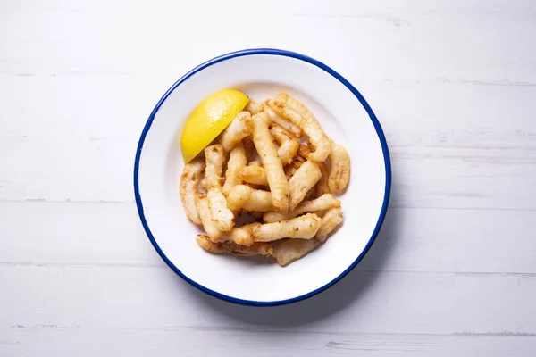 Fried squid tapa with lemon. Traditional recipe from the north of Spain of squid strips.