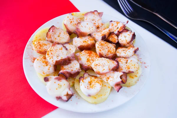 Galician octopus tapa. Sliced fresh octopus served on potatoes cooked with olive oil and red paprika. Traditional recipe in the region of Galicia in Spain.