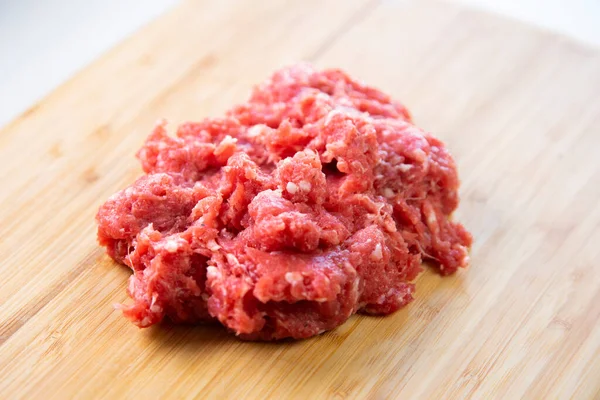 Premium minced beef on wood base on a white background.