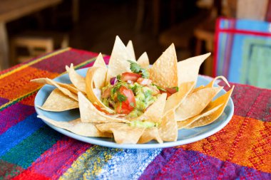 Guacamole soslu cips. Nachos Meksika kökenli bir yemektir, özel bir peynirle kaplanmış kızarmış mısır tortilla parçalarından oluşur..