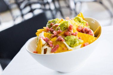 Guacamole soslu cips. Nachos Meksika kökenli bir yemektir, özel bir peynirle kaplanmış kızarmış mısır tortilla parçalarından oluşur..