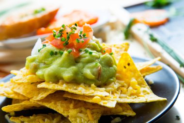 Guacamole soslu cips. Nachos Meksika kökenli bir yemektir, özel bir peynirle kaplanmış kızarmış mısır tortilla parçalarından oluşur..