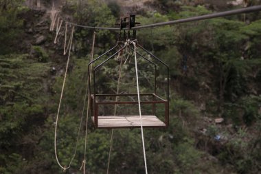 Malzeme taşımak için Oroya ya da Peru ormanındaki bir nehirdeki insanları. Halat boyunca uzanan iki halkadan sarkıtılmış sepet..