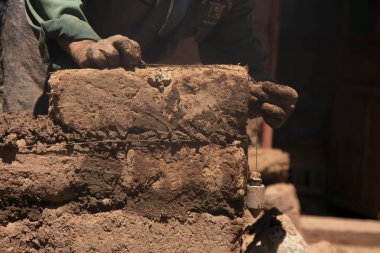 Elleriyle kerpiç tuğlalı ve çamurlu bir ev inşa eden bir adam. Peru 'daki Titicaca Gölü' nün Llachon bölgesi.