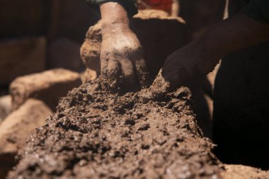 Elleriyle kerpiç tuğlalı ve çamurlu bir ev inşa eden bir adam. Peru 'daki Titicaca Gölü' nün Llachon bölgesi.