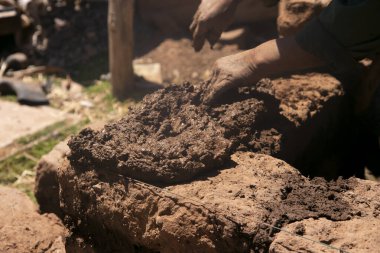 Elleriyle kerpiç tuğlalı ve çamurlu bir ev inşa eden bir adam. Peru 'daki Titicaca Gölü' nün Llachon bölgesi.