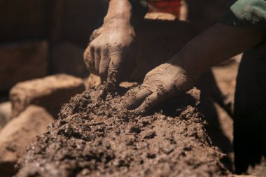 Elleriyle kerpiç tuğlalı ve çamurlu bir ev inşa eden bir adam. Peru 'daki Titicaca Gölü' nün Llachon bölgesi.