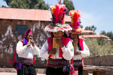 Taquile, Peru; 1 Ocak 2023: Peru 'nun Taquile adasında yaşayanlar, adanın ana meydanında bir etkinlikte dans edip müzik çalıyorlar..