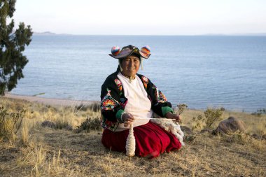 Llachon, Peru; 1 Ocak 2023: Titicaca Gölü 'ndeki Llachon yarımadasında yün ile çalışan bir kadın.