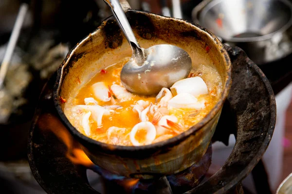 Cooking squid with red curry at a street food stall in Bangkok, Thailand.