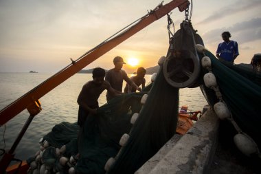 Koh Yao, Tayland; 1 Ocak 2023: Balıkçılar gün batımında Koh Yao limanında bir tekneden avlanıyorlar.