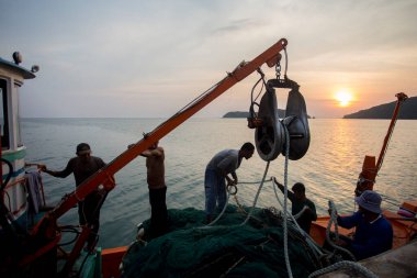 Koh Yao, Tayland; 1 Ocak 2023: Balıkçılar gün batımında Koh Yao limanında bir tekneden avlanıyorlar.