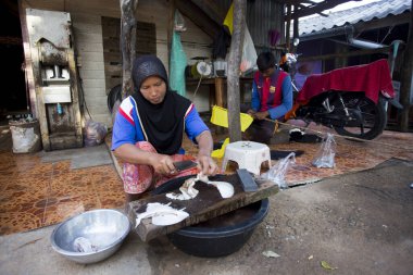 Koh Yao, Tayland; 1 Ocak 2023: Bir balıkçı köyünde mürekkep balığını temizleyip kurutan kadın.