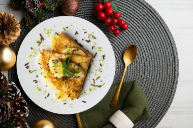 Limon suyuyla marine edilmiş muz parçalarıyla dolu krep Noel süsleme elementleriyle dolu bir masada..