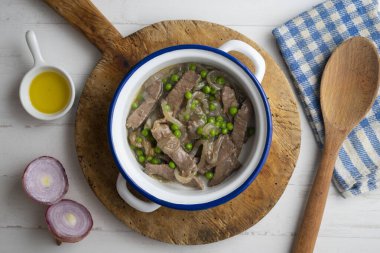 Biftek şeritleri soğan ve bezelye ile pişirilir..