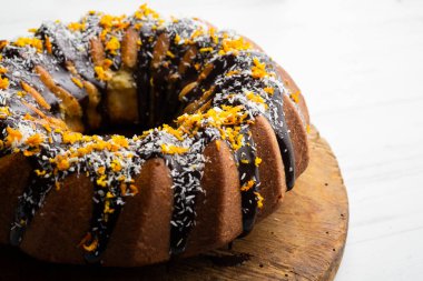 Turuncu ve hindistan cevizli kek yuvarlak kalıplı ve koyu çikolatayla kaplı..