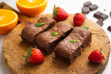 Çikolatalı kek porsiyonlara bölünmüş ve çilek ve nane ile süslenmiş..