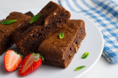 Çikolatalı kek porsiyonlara bölünmüş ve çilek ve nane ile süslenmiş..