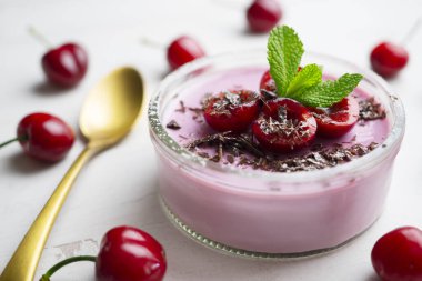 Vişneli panna cotta taze meyve ve rendelenmiş çikolatayla servis edilir..