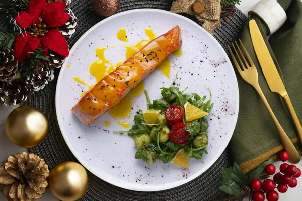 烤鲑鱼配橙汁和沙拉 典型的地中海沿岸菜 圣诞食品放在装饰有圣诞图案的桌子上 — 图库照片