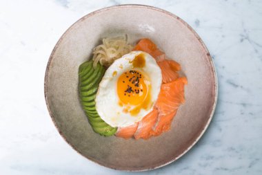 Kızarmış yumurta, avokado, soğan, kırmızı biber ve diğer sebzelerle birlikte teriyaki somon donburi. Tipik Japon yemeği..