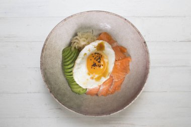 Kızarmış yumurta, avokado, soğan, kırmızı biber ve diğer sebzelerle birlikte teriyaki somon donburi. Tipik Japon yemeği..