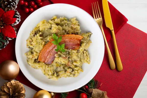Trinxat de la Cerdaa. Kuzey Katalonya 'nın tipik tarifi. Beyaz lahana, patates ve pastırma ile pişirilmiş. Noel motifleriyle süslenmiş bir masada servis edilen Noel yemeği..