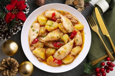 Kırmızı biberli mürekkep balığı güveci. Tipik İspanyol tapa tarifi. Noel motifleriyle süslenmiş bir masada servis edilen Noel yemeği..