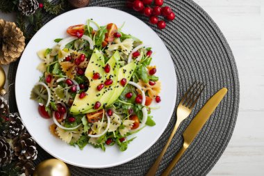 Makarna yayları, avokado, kiraz domatesleri, nar ve susamlı argula salatası Noel motifleriyle süslenmiş bir masada servis edilir..