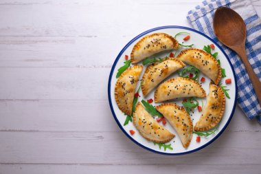 Geleneksel tarifle yapılmış Arjantin börekleri. Kırmızı biber ve roka ile süslenmiş havadan çekilmiş..