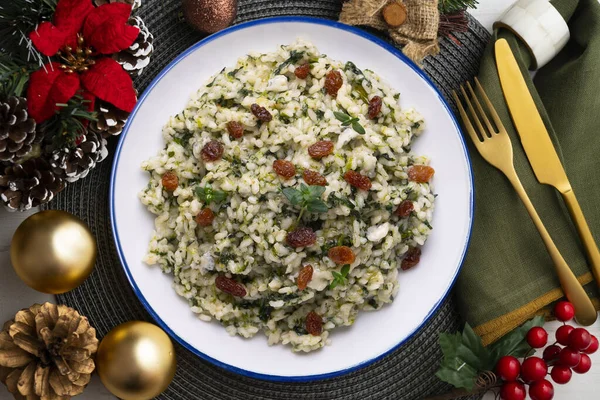 Rice with spinach and raisins. vegan recipe. Christmas food served on a table decorated with Christmas motifs.