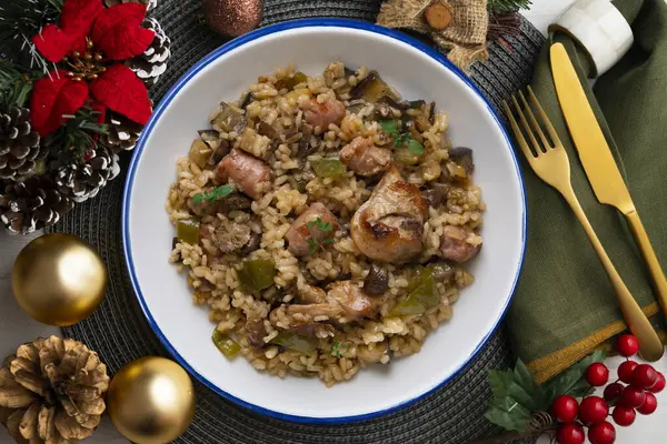 Rice paella with rabbit, sausages and green beans. Tapa traditional recipe in Valencia, Spain. Christmas food served on a table decorated with Christmas motifs.