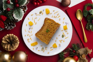 Lezzetli vejetaryen havuç ve bademli mandalinalı kek. Noel motifleriyle süslenmiş bir masada servis edilen Noel yemeği..