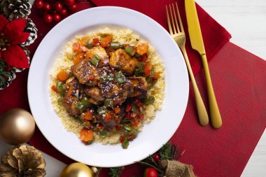 Kuskus soslu Fas usulü marine edilmiş tavuk. Noel süslemeleri olan bir masada servis edilen yemekler..