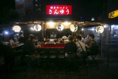 Fukuoka, Japonya; 1 Ekim 2023: İnsanlar Hakata Körfezi 'nde bir Yatai' de yiyip içiyorlar. Yatai, Japonya 'da ramen veya diğer yiyecekleri satan küçük bir yiyecek dükkanıdır..