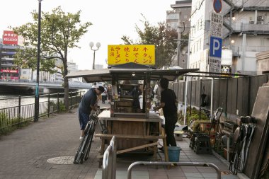 Fukuoka, Japonya; 1 Ekim 2023: Hakata Körfezi 'nde insanlar bir Yatai hazırlıyor. Yatai, Japonya 'da ramen veya diğer yiyecekleri satan küçük bir yiyecek dükkanıdır..