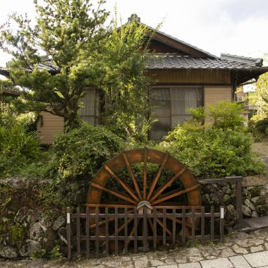 Su çarkı, sokaklar ve Japonya 'nın Kiso Vadisi' ndeki Nakasendo yolu boyunca Magome Juku kasabasındaki geleneksel Japon evleri..