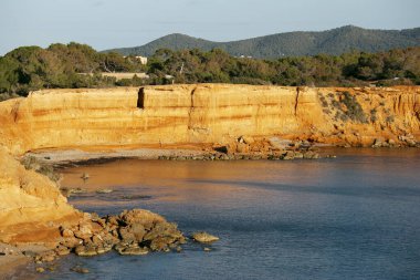 İbiza 'daki Sa Caleta plajı. Ibiza adasında kırmızı kaya ve kristal berrak suları olan güzel bir sahil..