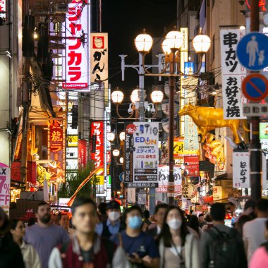 Osaka, Japonya; 20 Ekim 2023: Dotonbori caddelerinde sokak yemekleri ve gece hayatı dolu restoranlar ve turistler.