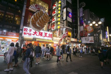 Osaka, Japonya; 20 Ekim 2023: Dotonbori caddelerinde sokak yemekleri ve gece hayatı dolu restoranlar ve turistler.