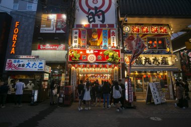 Osaka, Japonya; 20 Ekim 2023: Dotonbori caddelerinde sokak yemekleri ve gece hayatı dolu restoranlar ve turistler.