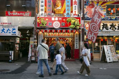 Osaka, Japonya; 20 Ekim 2023: Dotonbori caddelerinde sokak yemekleri ve gece hayatı dolu restoranlar ve turistler.