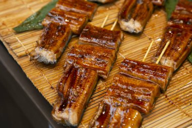 Roasted skewered eel at a food market in the city of Osaka in Japan. clipart