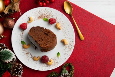 Çikolatalı pastanın nefis bir parçası genel bir perspektiften görülüyor. Noel süsleme masası.