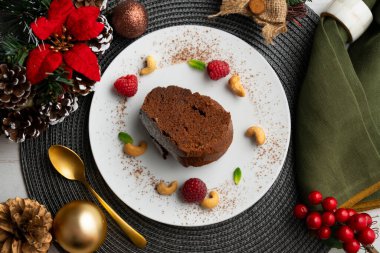 Çikolatalı pastanın nefis bir parçası genel bir perspektiften görülüyor. Noel süsleme masası.