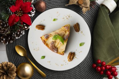 Taze armutlu lezzetli pasta ve Noel süslemeleri olan bir masada kuru üzüm..