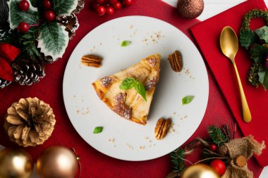 Taze armutlu lezzetli pasta ve Noel süslemeleri olan bir masada kuru üzüm..