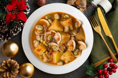 Patates ve fasulyeli midye yahnisi. Geleneksel İspanyol tarifi Noel süslemeleri masasında.